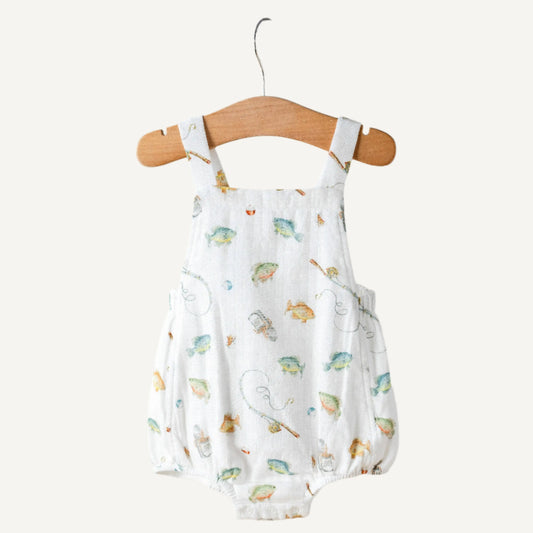 Baby romper with fishpattern on a wooden hanger against a light gray wall.
