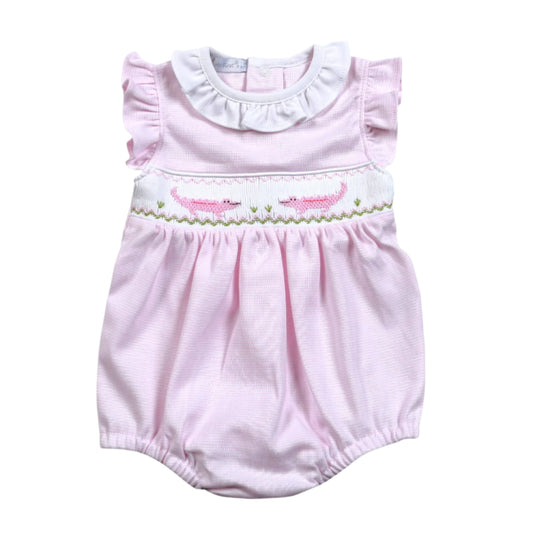 Pink baby romper with ruffled collar and embroidered details on a white background with alligators stiched
